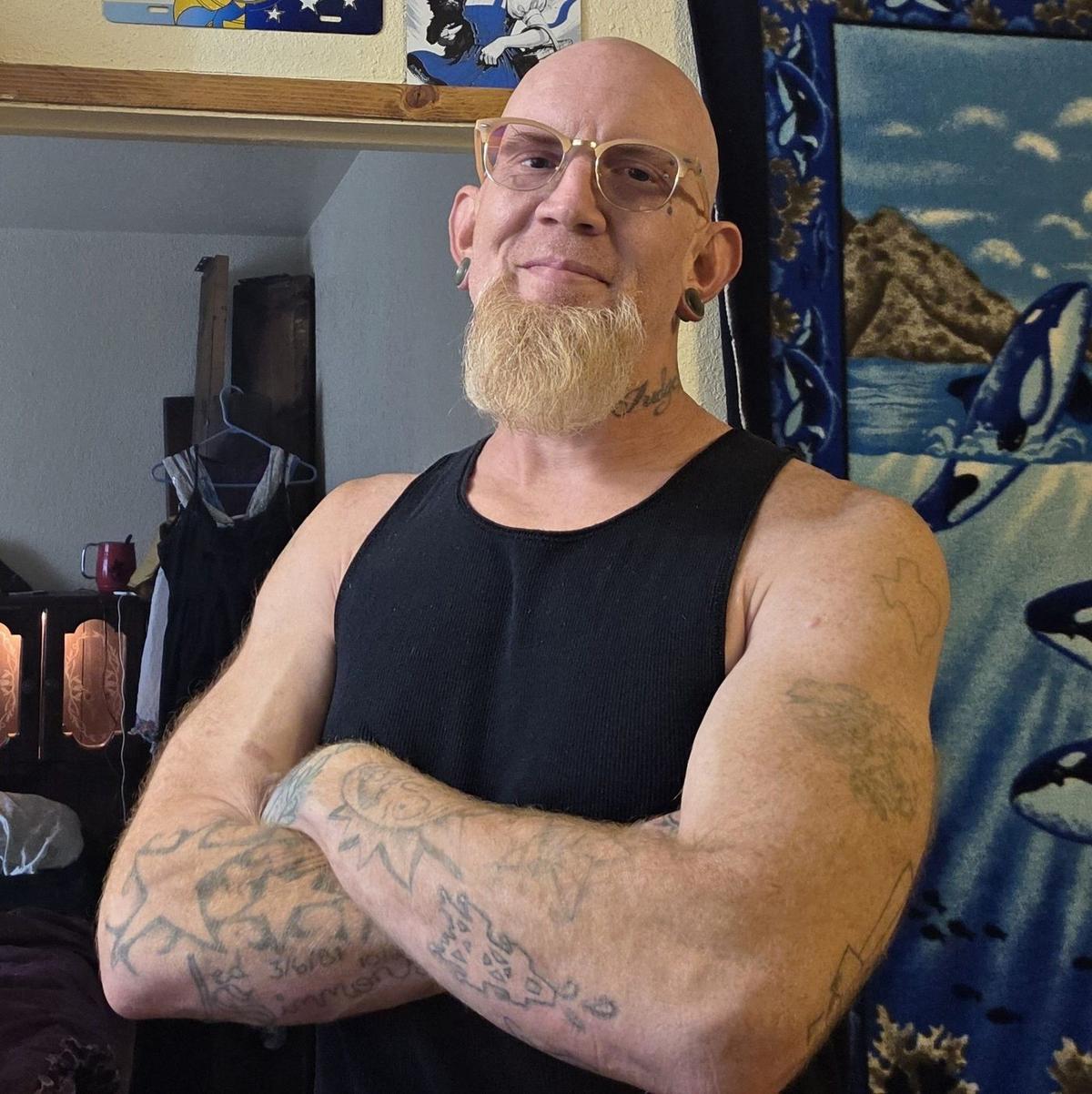 Author Michael Steilling, arms crossed, wearing a black tank top